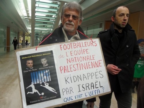 A protester's poster highlights Israel's detention of football players